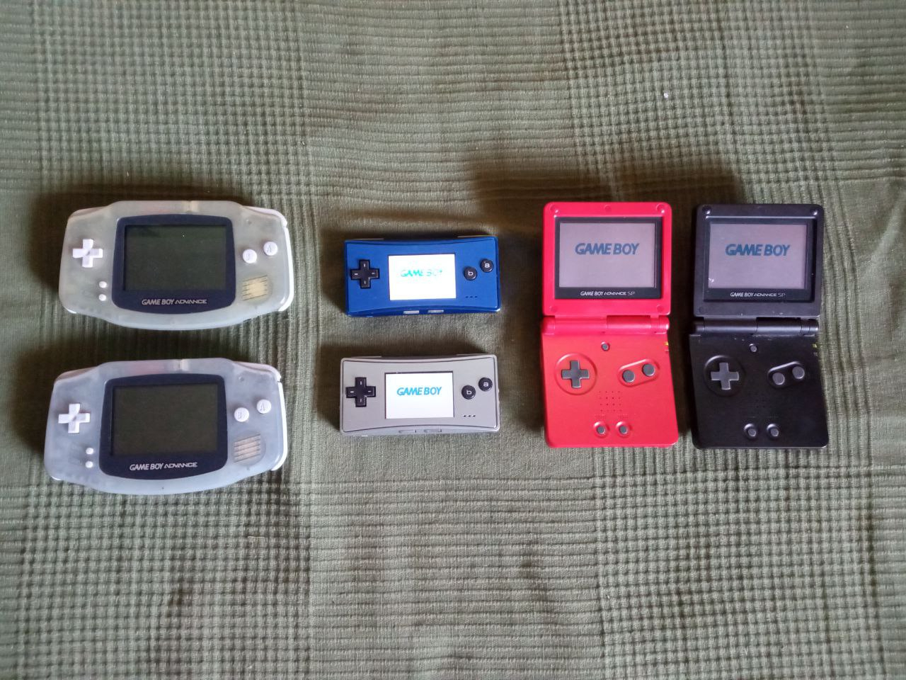 Collection of Game Boy Advance consoles, including two original models, two Game Boy Micro (one blue, one silver) and two Game Boy Advance SP (one red, one black)